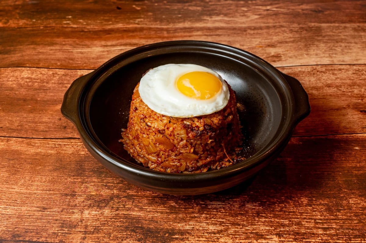 Kimchi fried rice topped with a fried egg in a black bowl