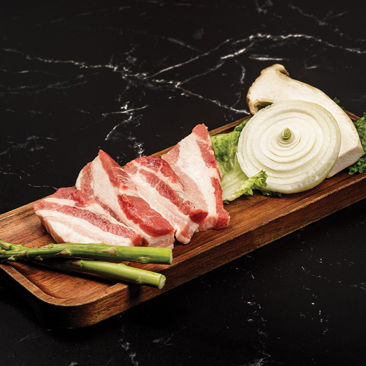 Thick slices of pork belly arranged for the tableside grill
